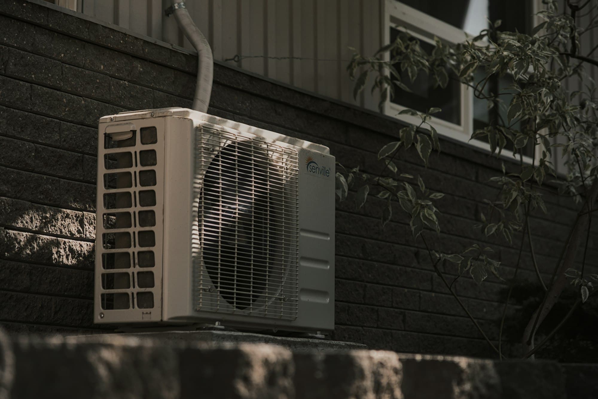 Unité extérieure de climatisation fixée sur un mur en briques