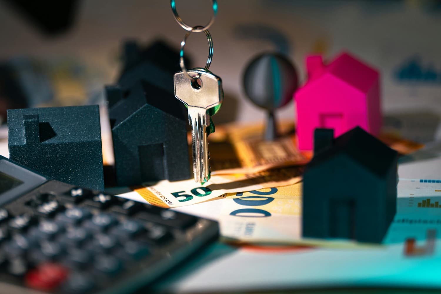 Maquettes de maisons, clé et billets en euros symbolisant les aides au financement